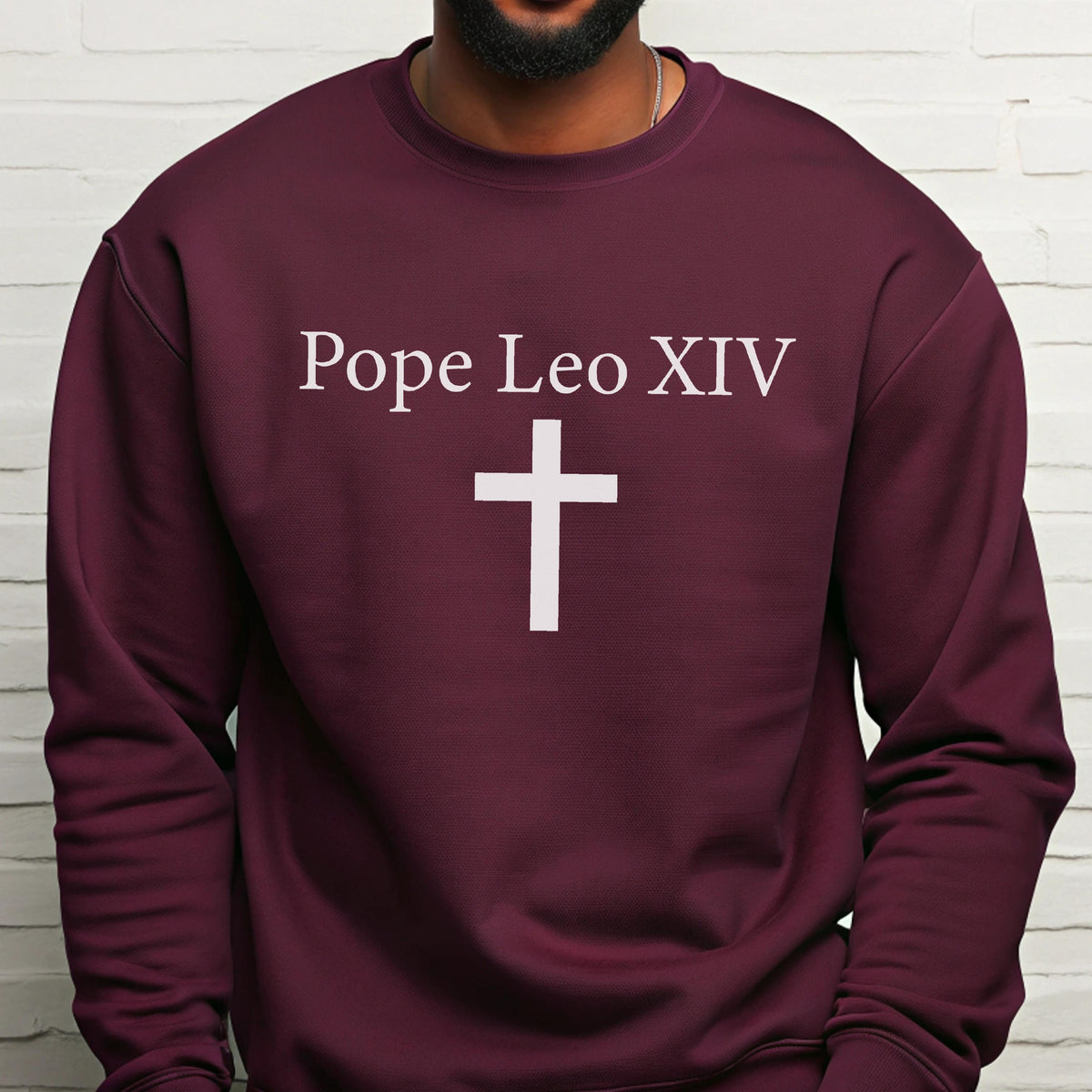 May include: A maroon sweatshirt with the text "Pope Leo XIV" above a white cross. The sweatshirt is a solid color and has a crew neck.