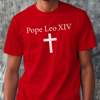 May include: Red t-shirt with the text "Pope Leo XIV" above a white cross. The shirt is a solid red color and has short sleeves. The text and cross are in a simple, clean font.