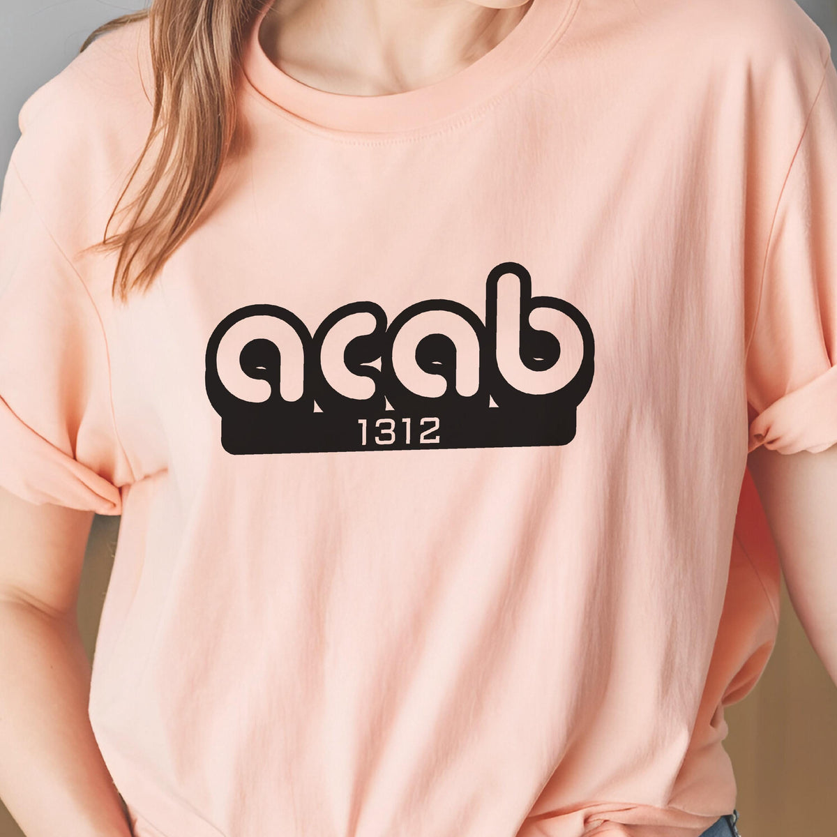 May include: A pink t-shirt with a black graphic that says "ACAB 1312".