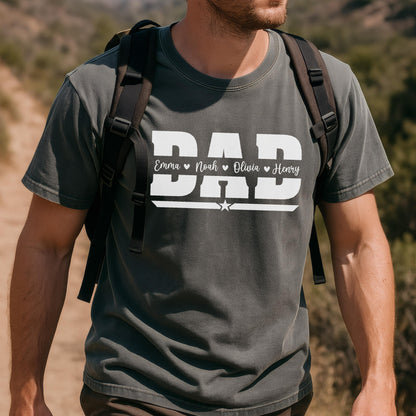 May include: Dark gray t-shirt with the word "DAD" in white block letters. Below the word "DAD" are the names "Emma", "Noah", "Olivia", and "Henry". A white star is below the names. The shirt is being worn by a person.