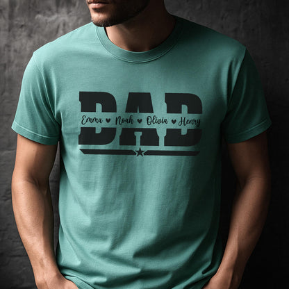May include: Teal-colored t-shirt with the word "DAD" in bold, black letters. Below the word "DAD" are the names Emma, Noah, Olivia, and Henry, each with a heart symbol. A star is below the names.
