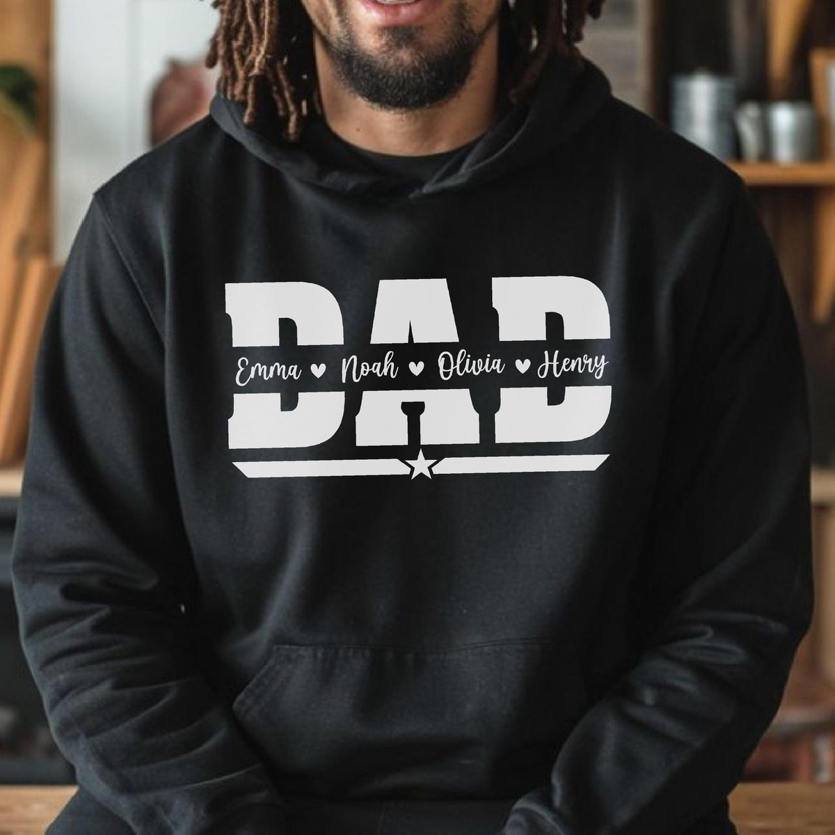 May include: Black hoodie with the word "DAD" in large white block letters. Below the word "DAD" are the names Emma, Noah, Olivia, and Henry, each with a heart symbol. A white star is centered below the names.