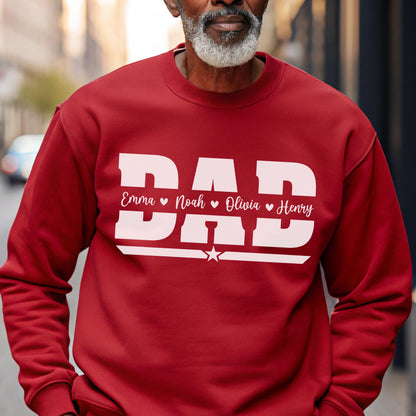 May include: A red sweatshirt with the word "DAD" in large white block letters. Below the word "DAD" are the names "Emma", "Noah", "Olivia", and "Henry" in white script, separated by hearts. A white star is below the names.