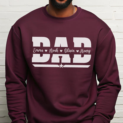 May include: A maroon sweatshirt with the word "DAD" in large white block letters. Below the word "DAD" are the names Emma, Noah, Olivia, and Henry, each with a heart symbol. A white star is centered below the names.