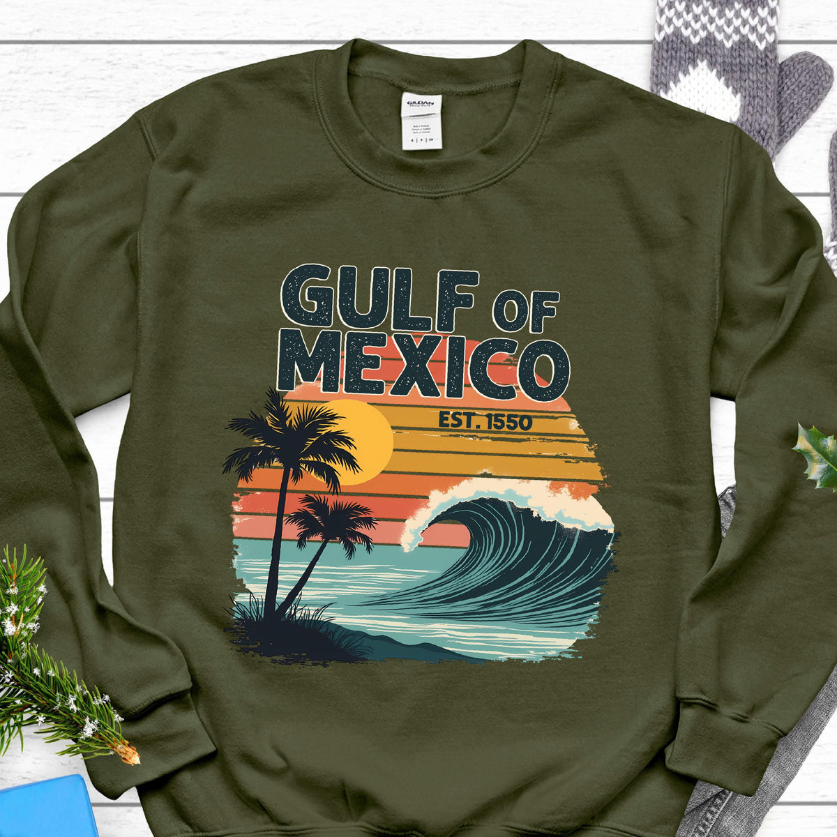 May include: A green sweatshirt with a retro-style graphic of a wave crashing on a beach with palm trees. The text "GULF OF MEXICO EST. 1550" is printed on the sweatshirt.