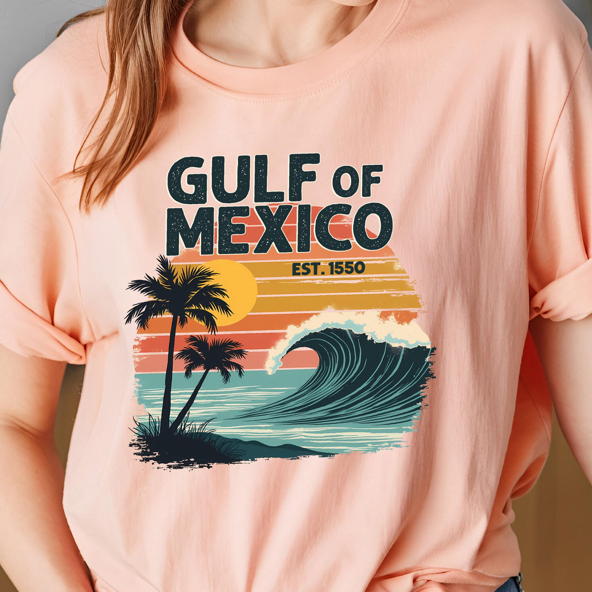 May include: A pink t-shirt with a retro-style graphic design featuring a wave, palm trees, and the text "GULF OF MEXICO EST. 1550".