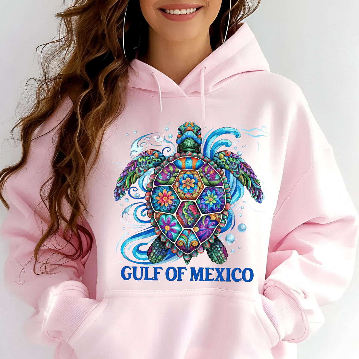 May include: Pink hooded sweatshirt featuring a colorful sea turtle design. The turtle has a patterned shell with floral and geometric elements, surrounded by blue water swirls. The text "GULF OF MEXICO" is printed below the turtle.