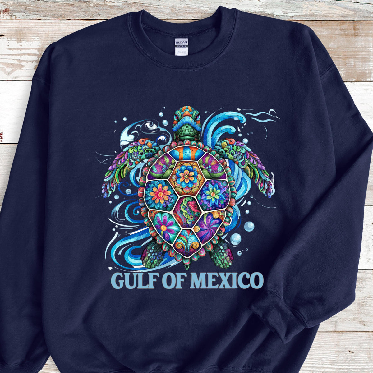May include: Navy blue sweatshirt featuring a colorful sea turtle design. The turtle has a vibrant, patterned shell with floral and geometric shapes in shades of blue, green, orange, and purple. The text "GULF OF MEXICO" is printed below the turtle.