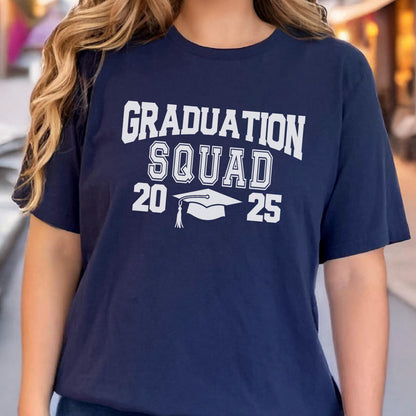 May include: Navy blue t-shirt with the words "GRADUATION SQUAD 2025" in white block letters. A white graduation cap graphic is centered below the word "SQUAD". The shirt is a short-sleeved crew neck.