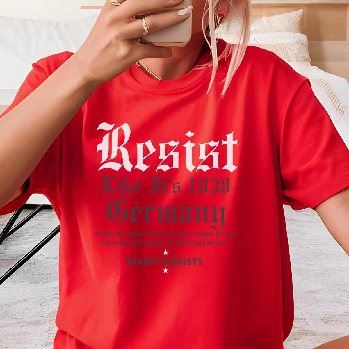 May include: Red t-shirt with white text that reads "Resist Like 1938 Germany" and a smaller line of text that reads "Resist Fascists".