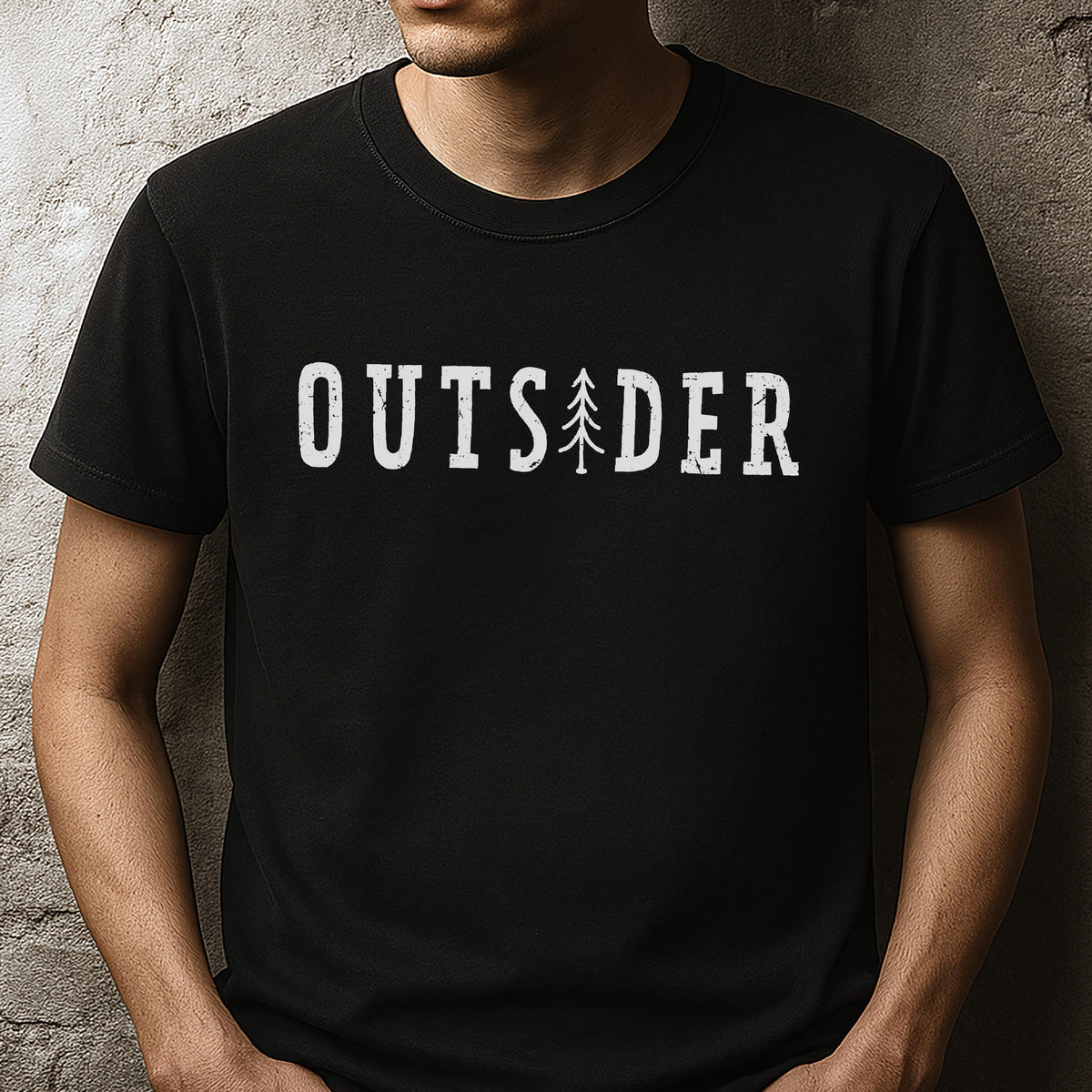May include: A black short-sleeved t-shirt featuring the white text OUTSIDER printed across the chest. The letter I is replaced by a stylized white pine tree graphic. The font has a distressed, weathered texture throughout the lettering.