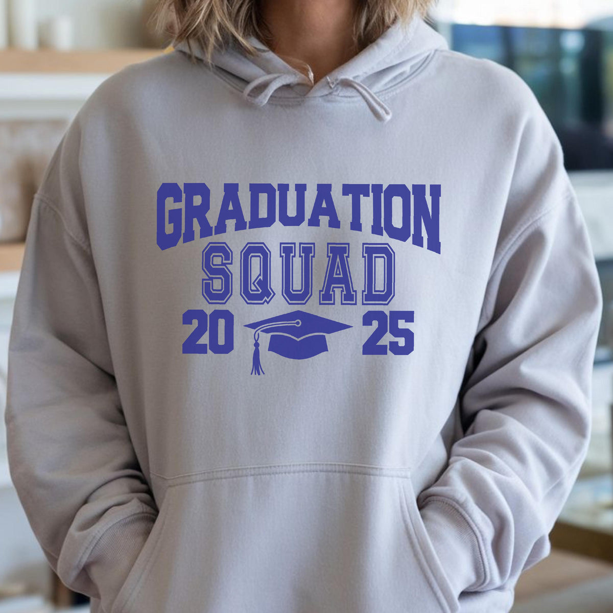 May include: A light gray hoodie with a front pocket and a drawstring hood. The front of the hoodie features the words "GRADUATION SQUAD" in blue block letters, along with the numbers "20" and "25" and a graduation cap graphic.