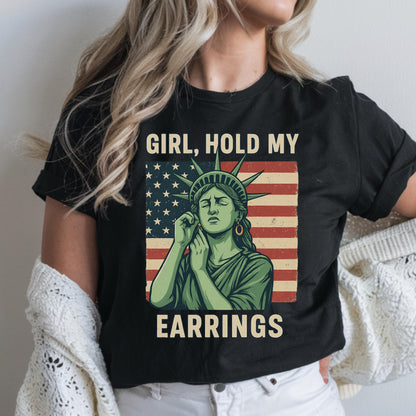 May include: Black t-shirt with a graphic of the Statue of Liberty holding an earring, with the text "Girl, hold my earrings" and an American flag background.