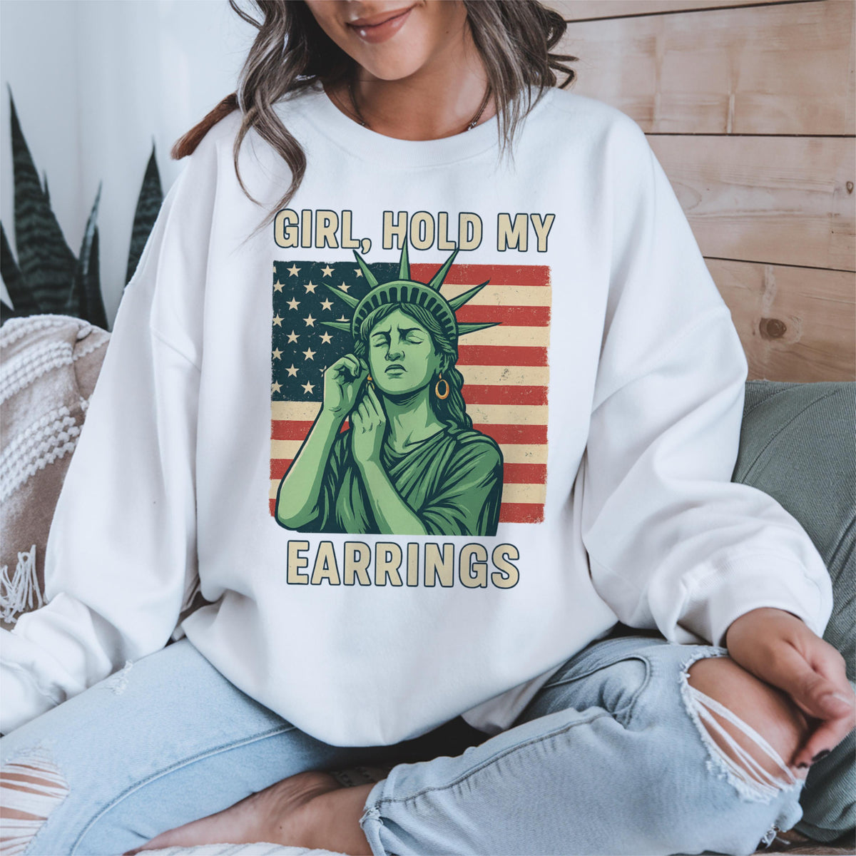 May include: White sweatshirt with a graphic of the Statue of Liberty holding an earring, with the text "Girl, hold my earrings" printed on the front.