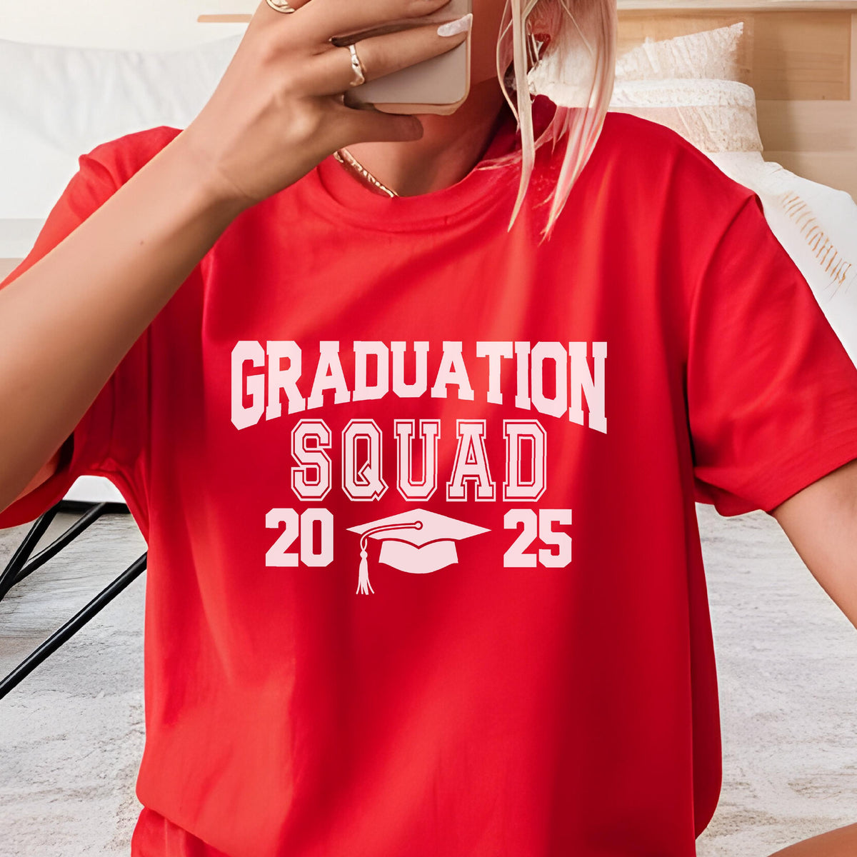 May include: A red t-shirt with the words "GRADUATION SQUAD 2025" in white block letters. A graduation cap graphic is centered below the text. The shirt is short-sleeved.
