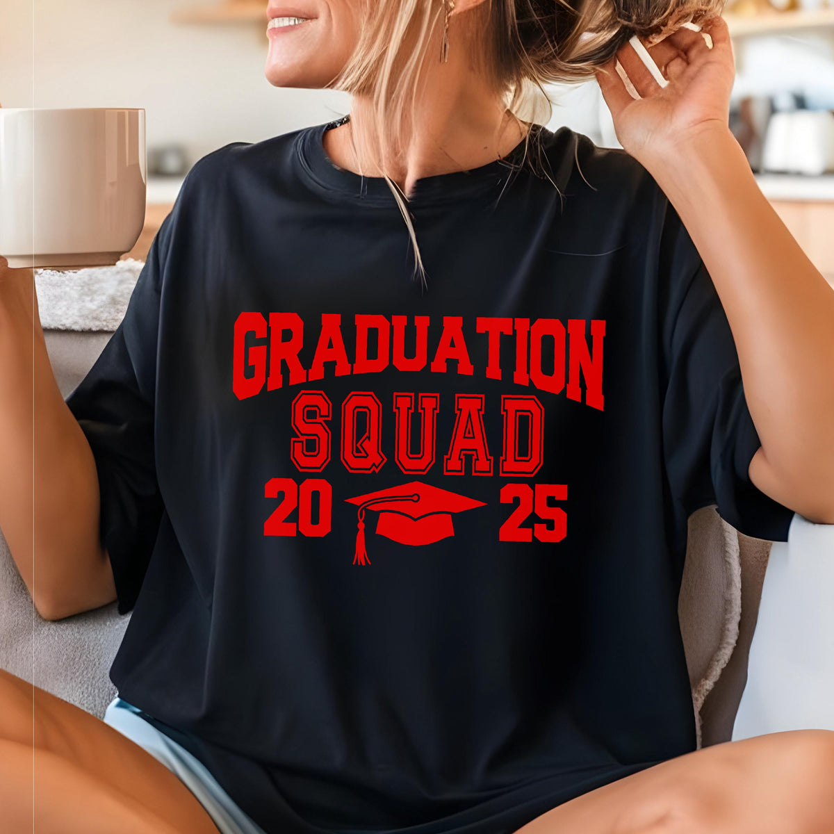 May include: Black t-shirt with the words "GRADUATION SQUAD 2025" in red block letters. A red graduation cap graphic is below the text. The shirt is a casual style.