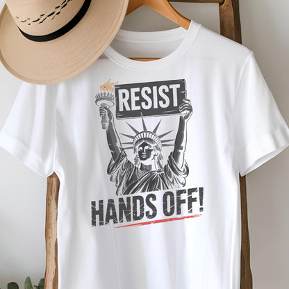 May include: White t-shirt with a graphic of the Statue of Liberty holding a sign that says "Resist" and the text "Hands Off!" printed below.