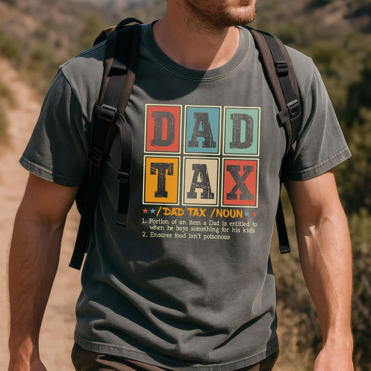 May include: Dark gray t-shirt with the text "DAD TAX" in a colorful, retro-style design. The shirt includes a definition of "DAD TAX" below the graphic. A casual, comfortable tee.