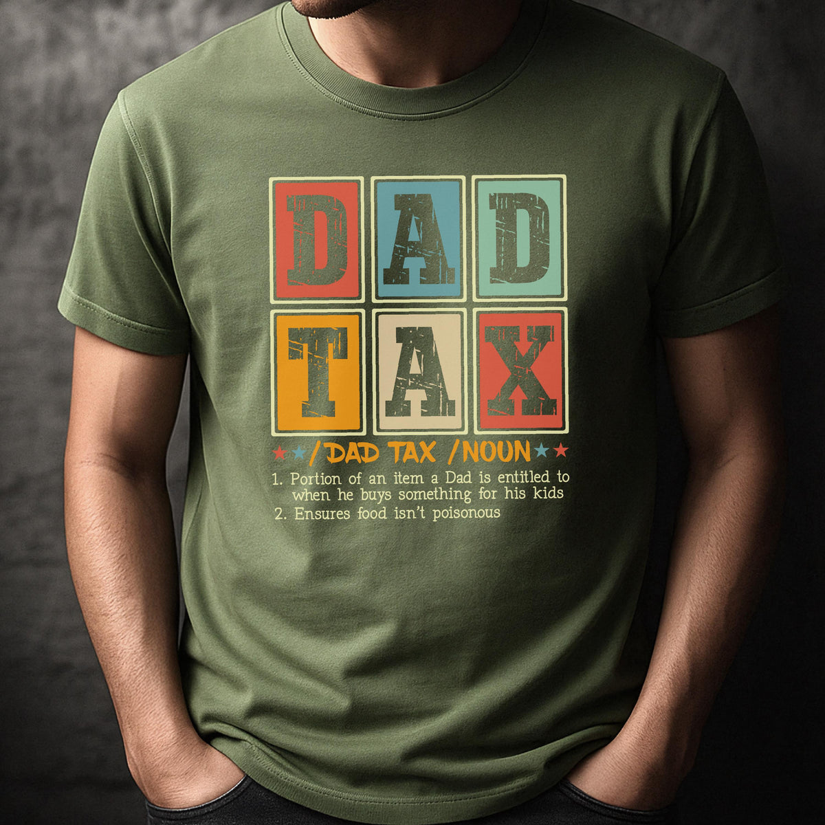 May include: Olive green t-shirt with a colorful graphic that reads "DAD TAX" in a block letter style. Below the text is a definition of "DAD TAX" and the word "NOUN".