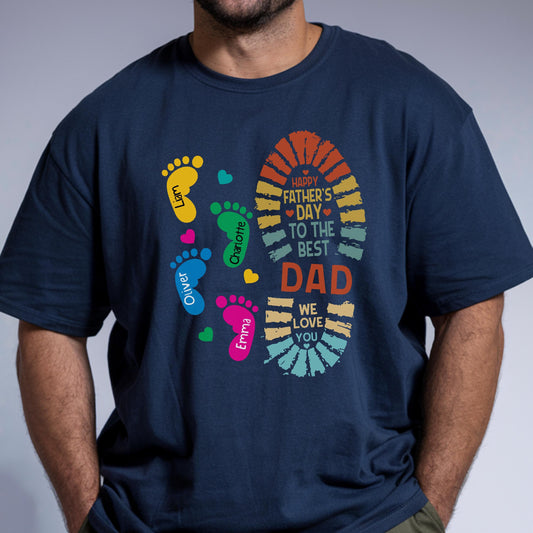 May include: Navy blue t-shirt with a colorful graphic for Father's Day. The design includes a large footprint with the text "Happy Father's Day to the Best Dad" and smaller footprints with names. Hearts are scattered around the footprints.