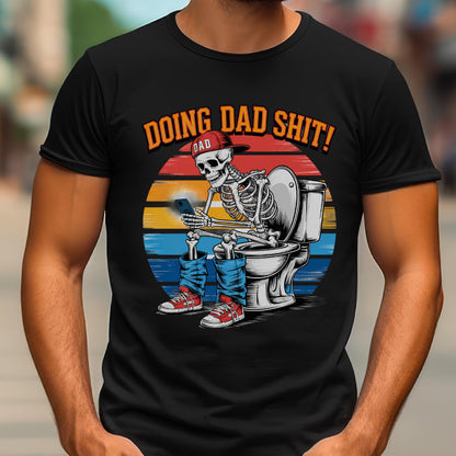 May include: Black t-shirt featuring a skeleton wearing a red cap that says "DAD" and blue jeans, sitting on a toilet while looking at a phone. The shirt has the text "DOING DAD SHIT!" in orange.