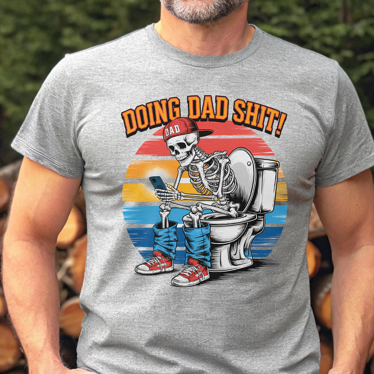 May include: Gray t-shirt with a graphic of a skeleton wearing a red cap and blue jeans, sitting on a toilet while using a smartphone. The text "DOING DAD SHIT!" is above the skeleton, with "DAD" on the cap.