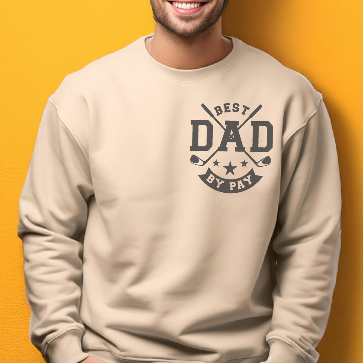 May include: Beige sweatshirt with a graphic that says "BEST DAD BY PAY" in dark gray. The design includes crossed golf clubs and stars. The sweatshirt is a neutral color.