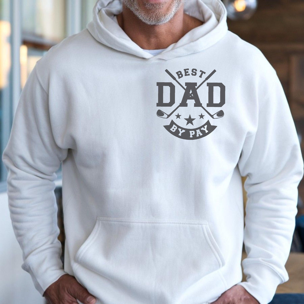 May include: A white hooded sweatshirt with a front pocket. The sweatshirt features a gray graphic that reads "BEST DAD BY PAY" with crossed golf clubs and stars.