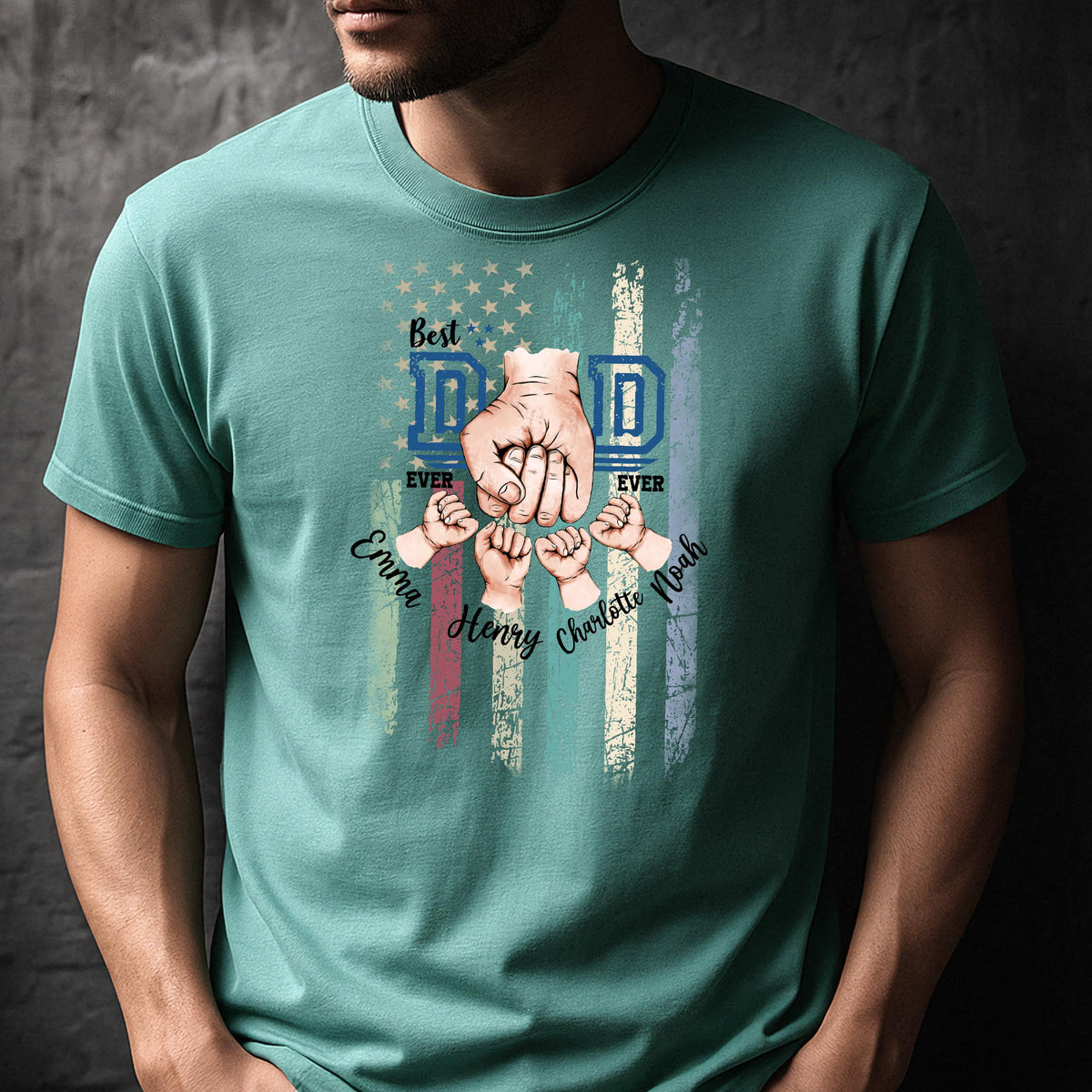 May include: Teal t-shirt with a graphic design featuring the words "Best Dad Ever" in blue, with a hand fist bump design and the names Emma, Henry, Charlotte, and Noah. The design incorporates an American flag motif.