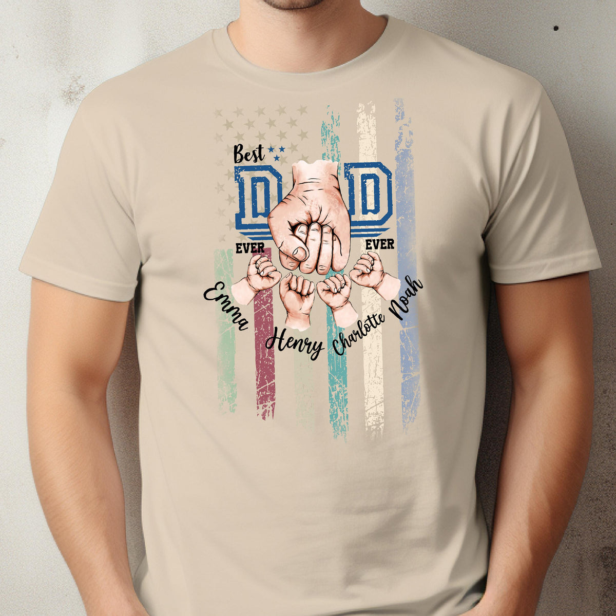May include: Beige t-shirt with a graphic design featuring the words "Best Dad Ever" in blue, a fist, and the names Emma, Henry, Charlotte, and Noah. The design includes a distressed American flag.