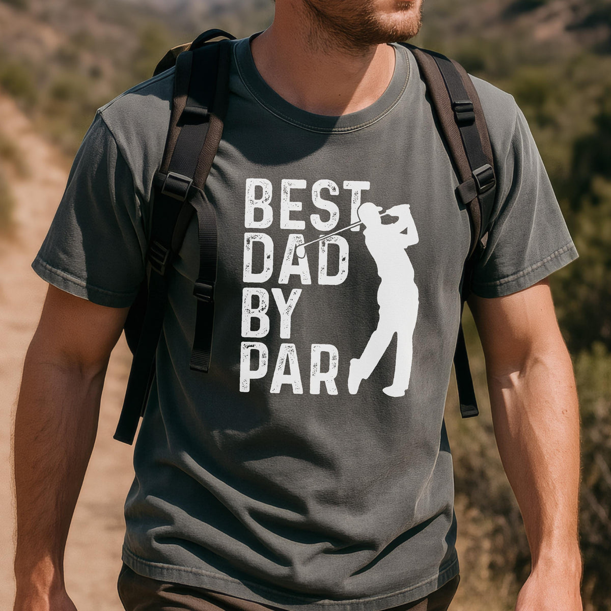 May include: A charcoal gray short-sleeve t-shirt featuring a white graphic print of a golfer in mid-swing. The text "BEST DAD BY PAR" is printed in a distressed white font to the left of the golfer silhouette. The shirt has a crew neckline.