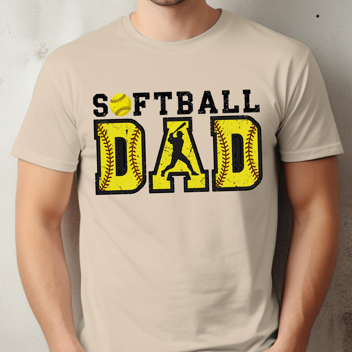 May include: A beige t-shirt with a distressed graphic design that says "Softball Dad" with a softball and a silhouette of a baseball player.