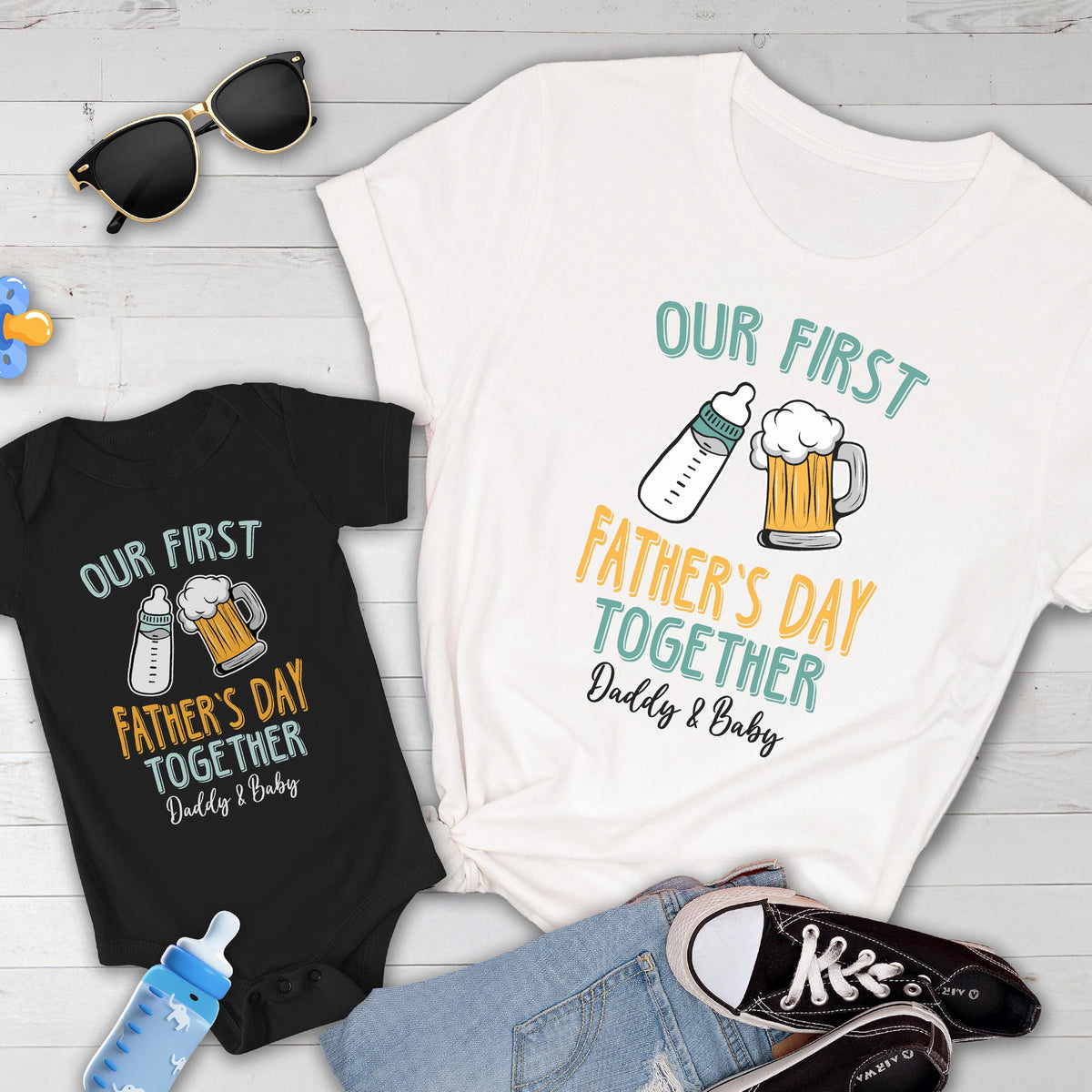 May include: A white t-shirt with the text "Our First Father's Day Together Daddy & Baby" and a graphic of a baby bottle and a beer mug. A black bodysuit with the same text and graphic is also shown.