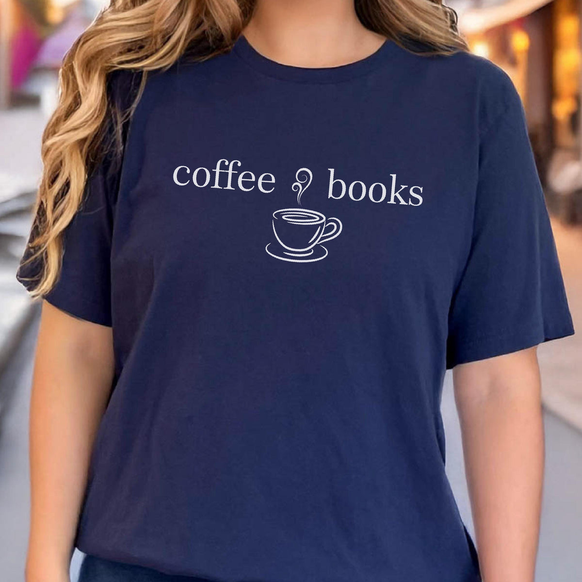 May include: Navy blue t-shirt with the words "coffee & books" and a coffee cup graphic in white. The shirt has short sleeves and a crew neck. The text and graphic are centered on the front.