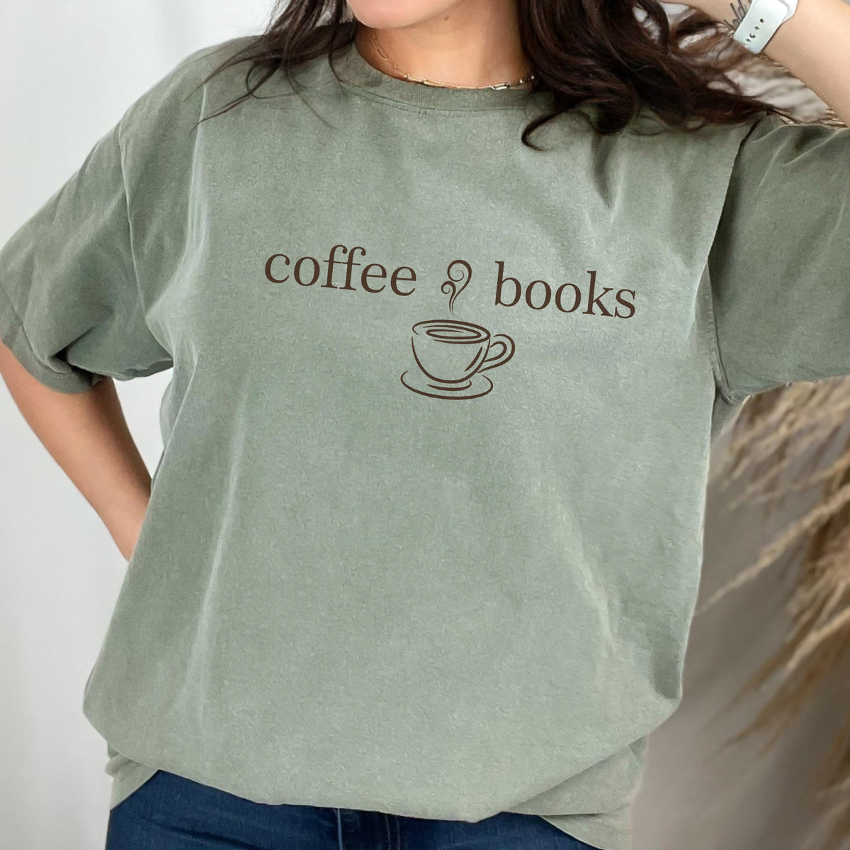 May include: A sage green short-sleeve t-shirt featuring the dark brown text coffee books and a graphic of a steaming coffee cup centered on the chest. The garment has a crew neckline and a relaxed fit, showcasing a solid color throughout.