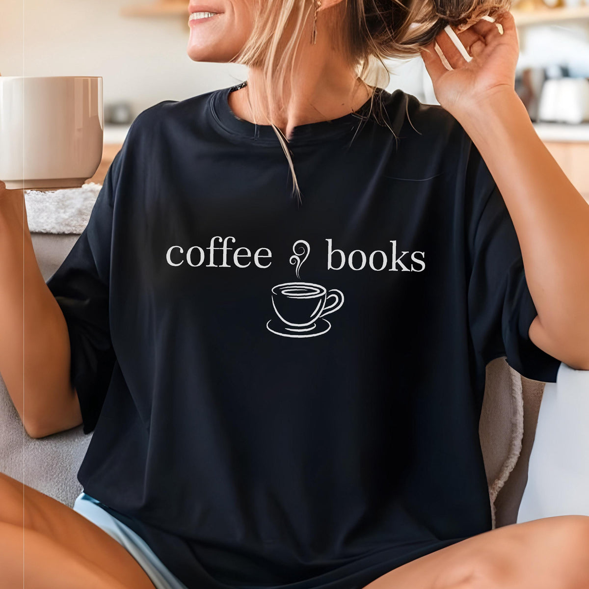 May include: A black short-sleeved t-shirt featuring white text that reads coffee books with a graphic of a steaming coffee cup centered between the words. The shirt has a crew neckline and a relaxed fit, made of a solid dark fabric.