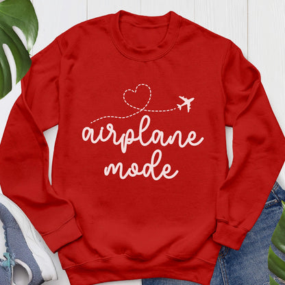 May include: A bright red long-sleeve crewneck sweatshirt featuring white text that reads airplane mode. Above the text is a white dashed line forming a heart shape that ends with a small airplane icon. The sweatshirt has ribbed cuffs and a ribbed neckline.