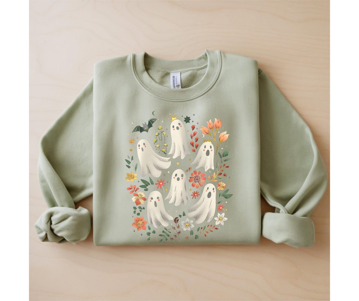 May include: Sage green sweatshirt featuring a whimsical design of friendly ghosts surrounded by colorful flowers, leaves, and a bat. The ghosts have smiling faces and are adorned with small crowns. A charming and festive garment for Halloween.