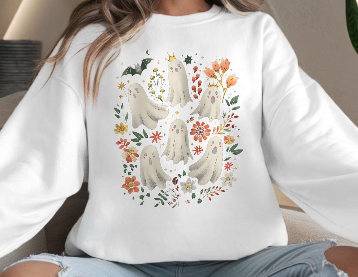 May include: White sweatshirt featuring a whimsical Halloween design. The design includes several cartoon ghosts, flowers, a bat, and stars. The ghosts are in various poses, surrounded by floral and botanical elements.