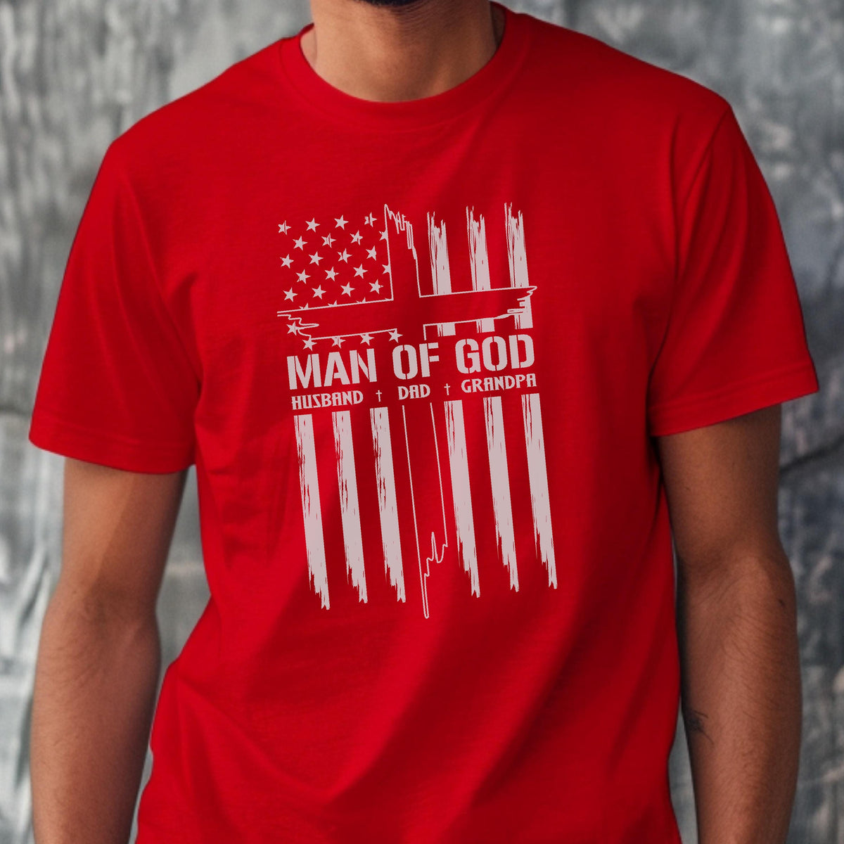 May include: Red t-shirt with a white graphic design. The design features a cross and the text "MAN OF GOD" above the words "HUSBAND + DAD + GRANDPA". The shirt is made of a soft material.