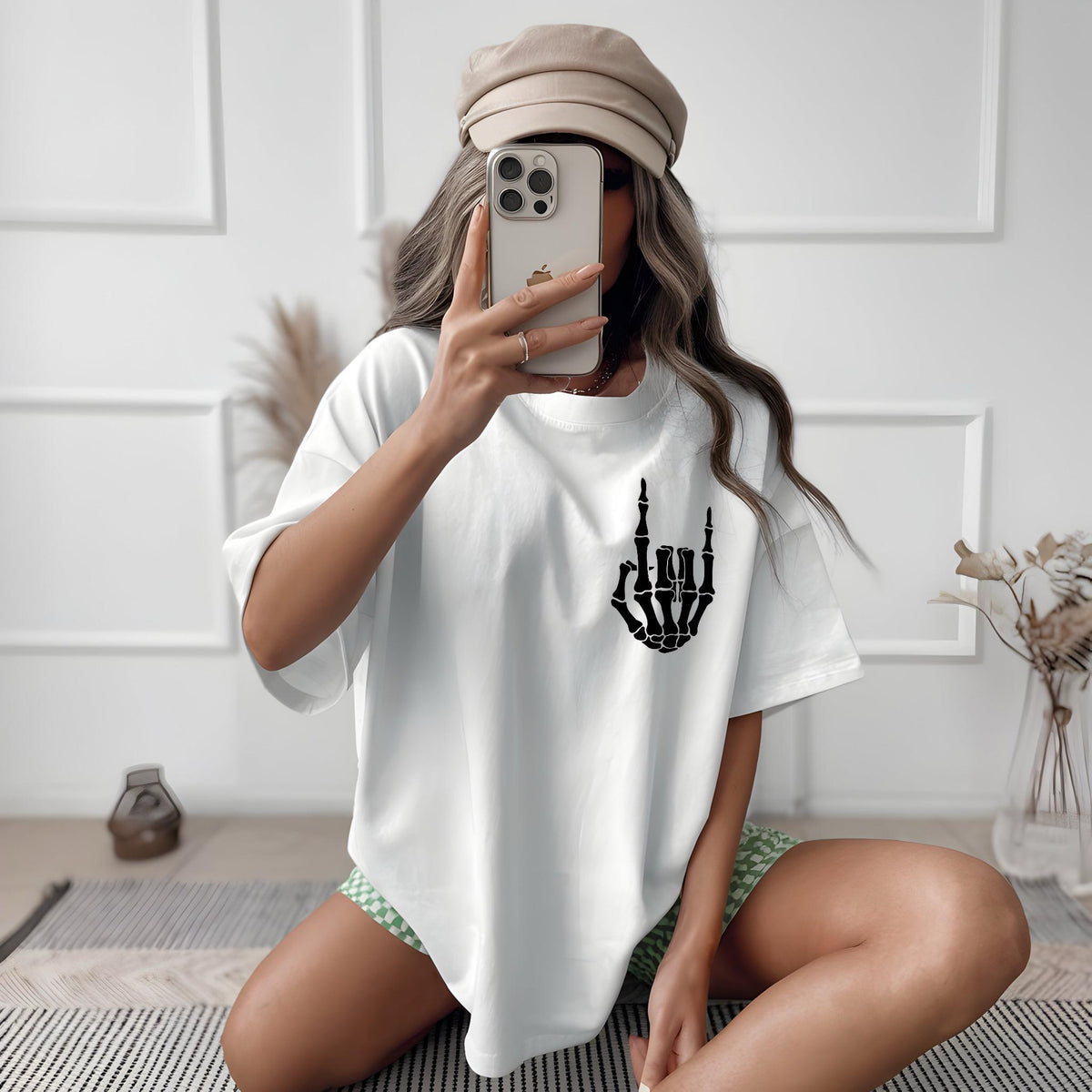 May include: White oversized t-shirt with a black skeleton hand graphic making the rock and roll hand gesture.