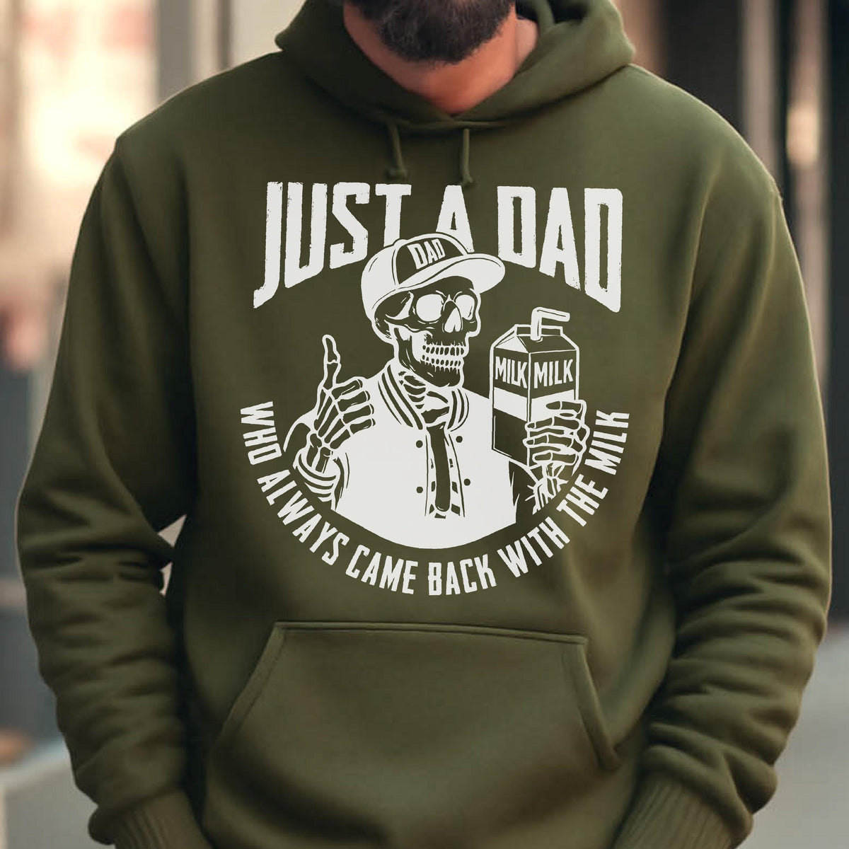 May include: Olive green hoodie with a white graphic of a skeleton wearing a baseball cap and holding a milk carton. The text reads "JUST A DAD WHO ALWAYS CAME BACK WITH THE MILK."
