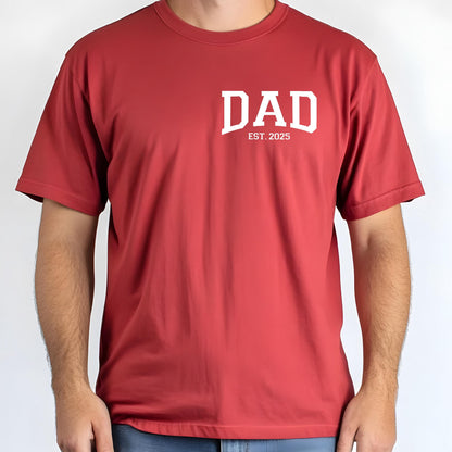 May include: Red short-sleeved t-shirt with white text that reads "DAD EST. 2025"