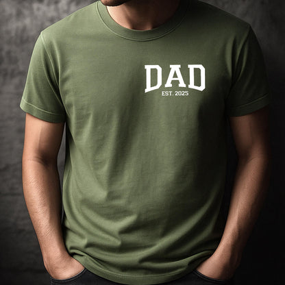 May include: A green short-sleeved t-shirt with the word "DAD" in white block letters and the text "EST. 2025" underneath.
