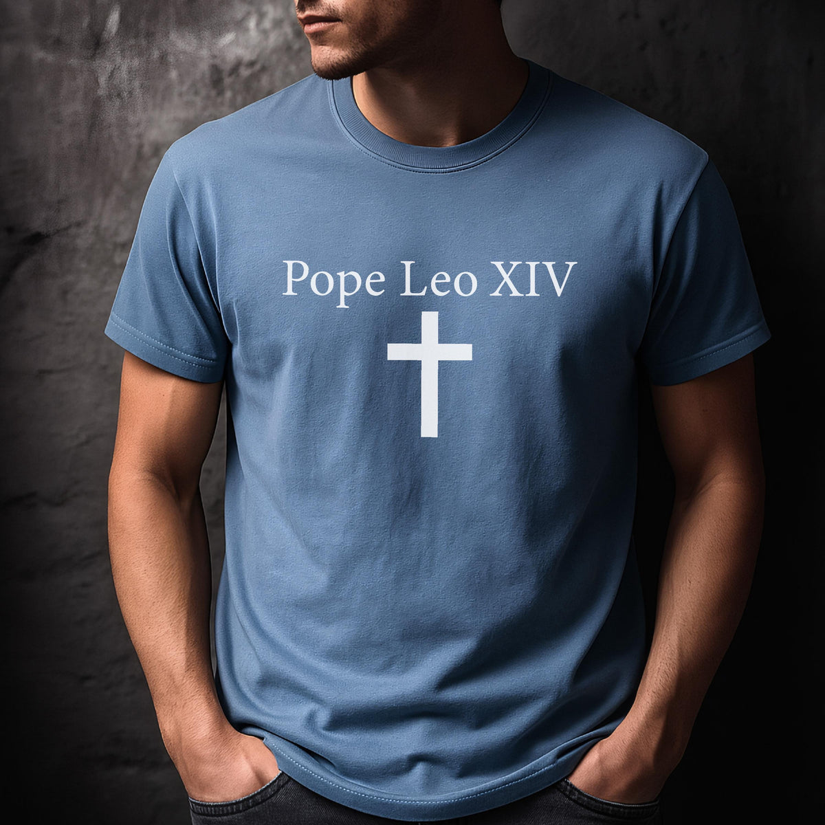 May include: A light blue t-shirt with the text "Pope Leo XIV" above a white cross. The shirt is a solid color and has short sleeves.