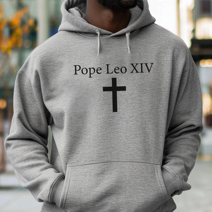 May include: A gray hooded sweatshirt with the text "Pope Leo XIV" above a black cross. The sweatshirt has a drawstring hood and a front pocket.