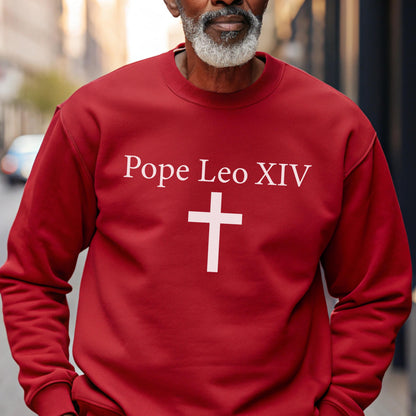 May include: A red sweatshirt with the text "Pope Leo XIV" above a white cross. The sweatshirt is a solid color and has long sleeves. The image is a close-up of the upper body.