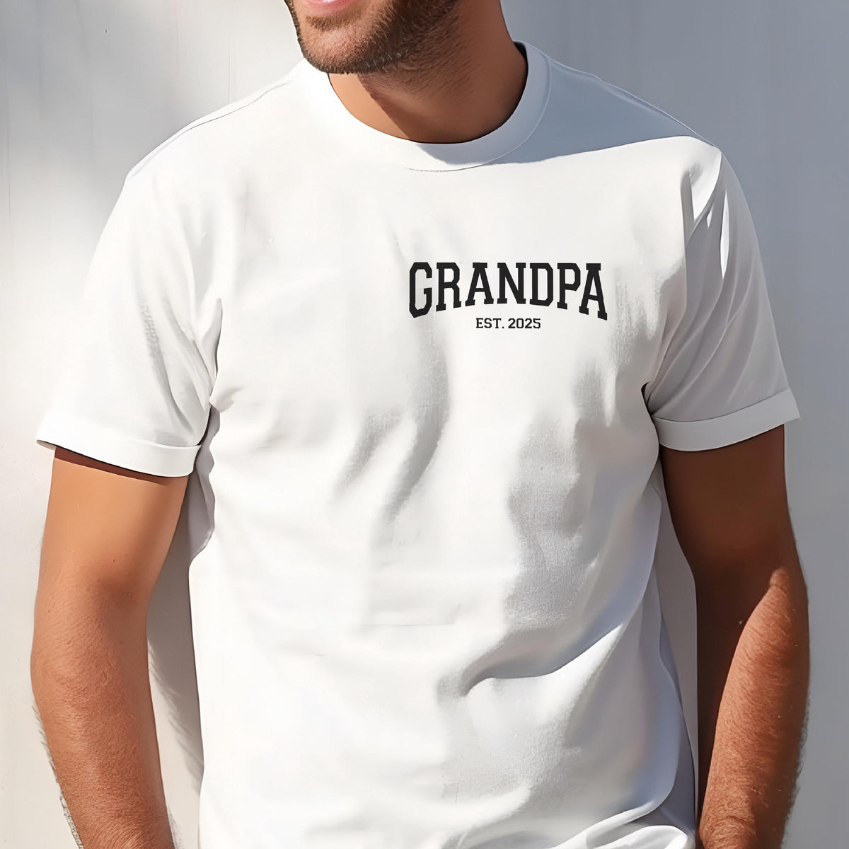 May include: White t-shirt with the word "GRANDPA" printed in black, with "EST. 2025" below it. The shirt has short sleeves and a crew neck.