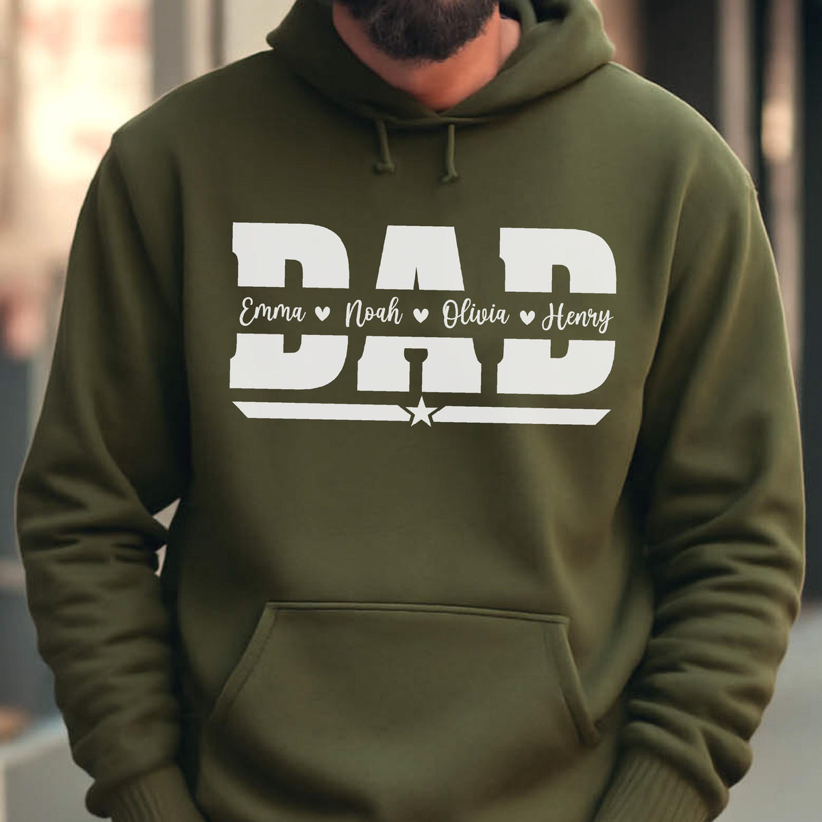May include: Olive green hoodie with a white graphic that says "DAD" in bold letters. Below the word "DAD" are the names "Emma", "Noah", "Olivia", and "Henry" with hearts. A star is below the word "DAD".