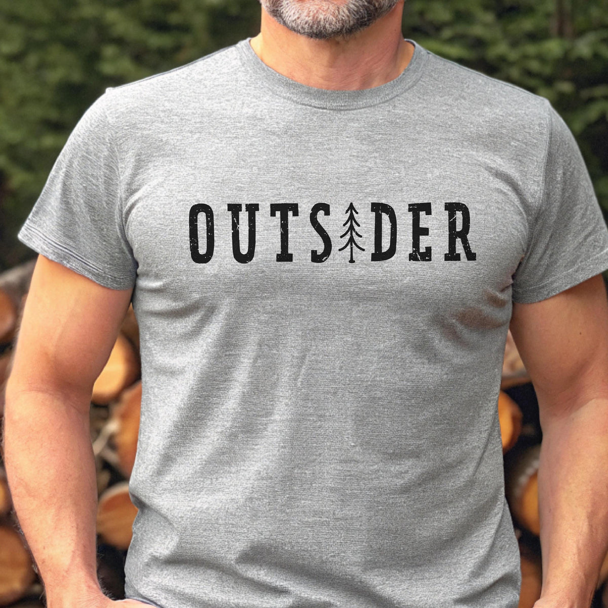 May include: A heather gray short-sleeved t-shirt featuring the black text "OUTSIDER" printed across the chest. The letter "I" in the word is replaced by a stylized graphic of a pine tree. The fabric has a visible textured knit pattern.